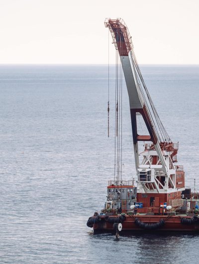 A red and white marine crane is at sea in cloudy weather.