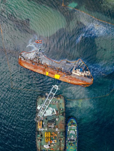 Top view of an old tanker that ran aground and overturned on the shore near the coast.
