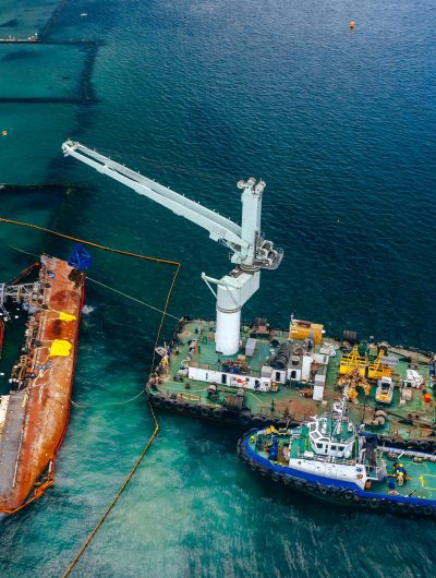 Top view of an old tanker that ran aground and overturned on the shore near the coast.